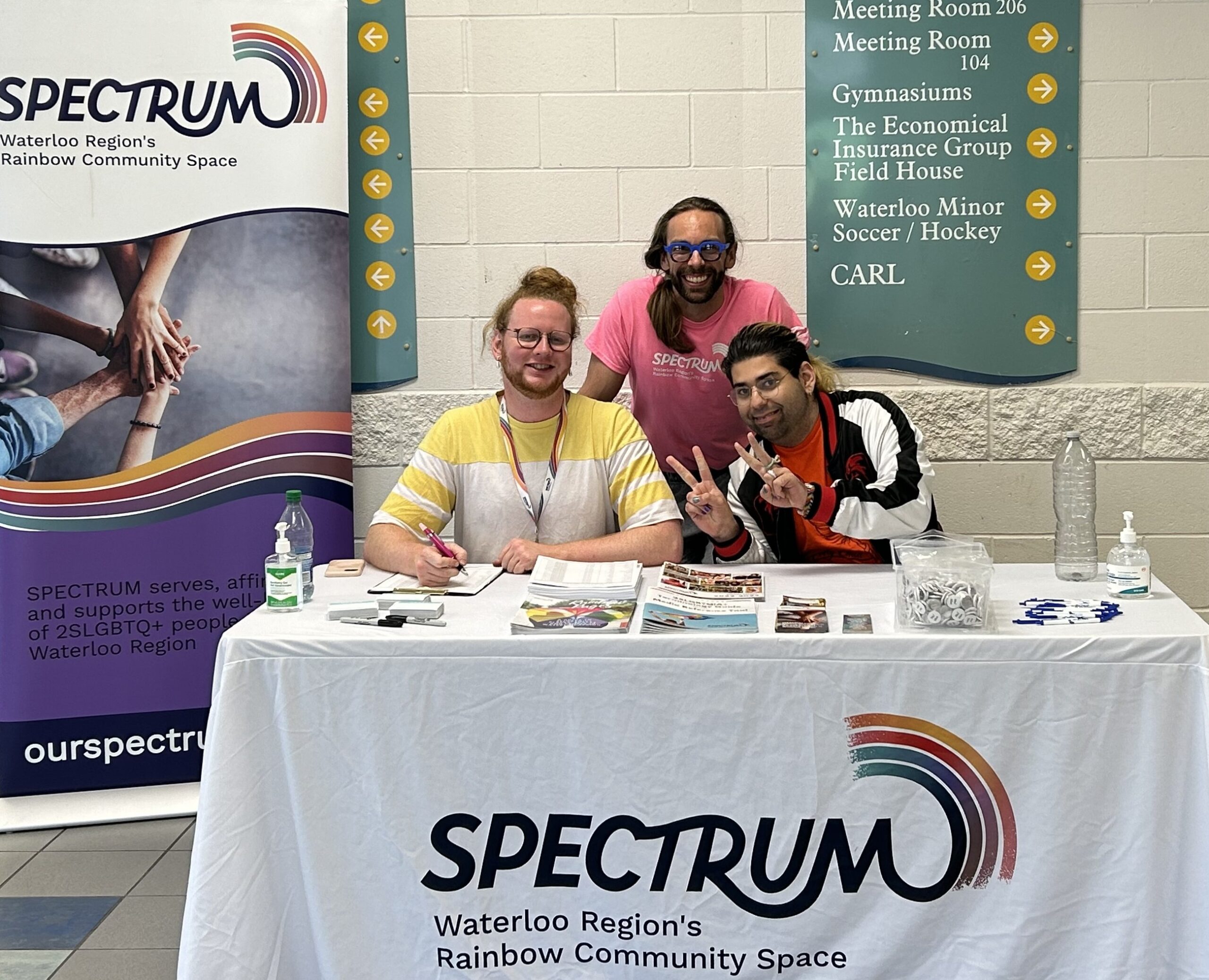 IMG_3417 A picture of three folks working at the Spectrum table, all smiling for the camera.