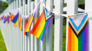 A white picket fence with progress flags hanging along it.