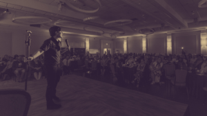 A photo in sepia tones of DeAnne Smith in front of a crowd at the 2025 gala.